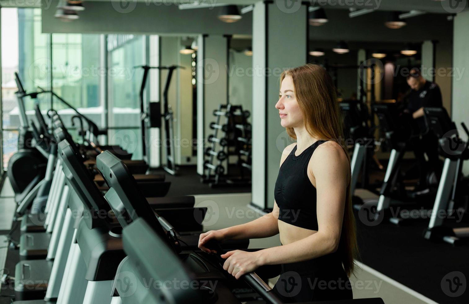 Happy athletic woman jogging on treadmills in a gym. photo
