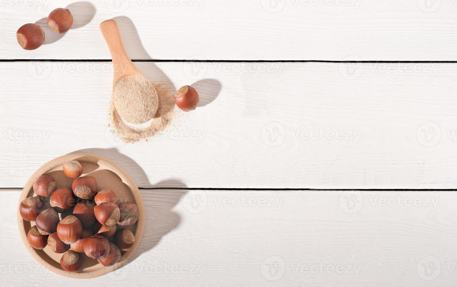 whole raw hazelnuts and hazelnut flour on white wooden table. paleo an ketogenic diet baking, keto cooking, gluten free food., top view, copy space photo