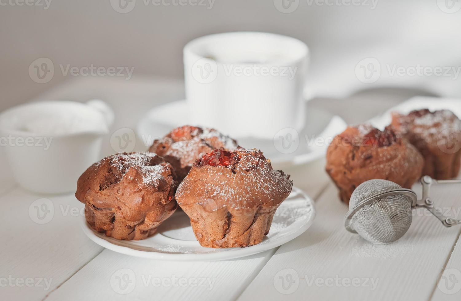 homemade chocolate muffins with berry filling and a cup of coffee on wooden table. home baking, tasty breakfast for weekend. photo