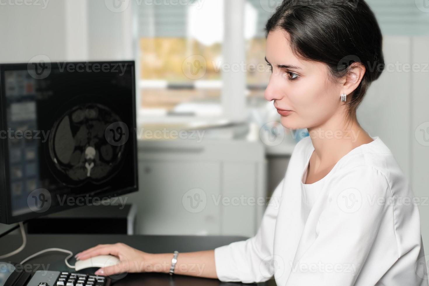 Radiologist woman reading a CT scan. Female doctor running CT scan from control room at hospital. photo