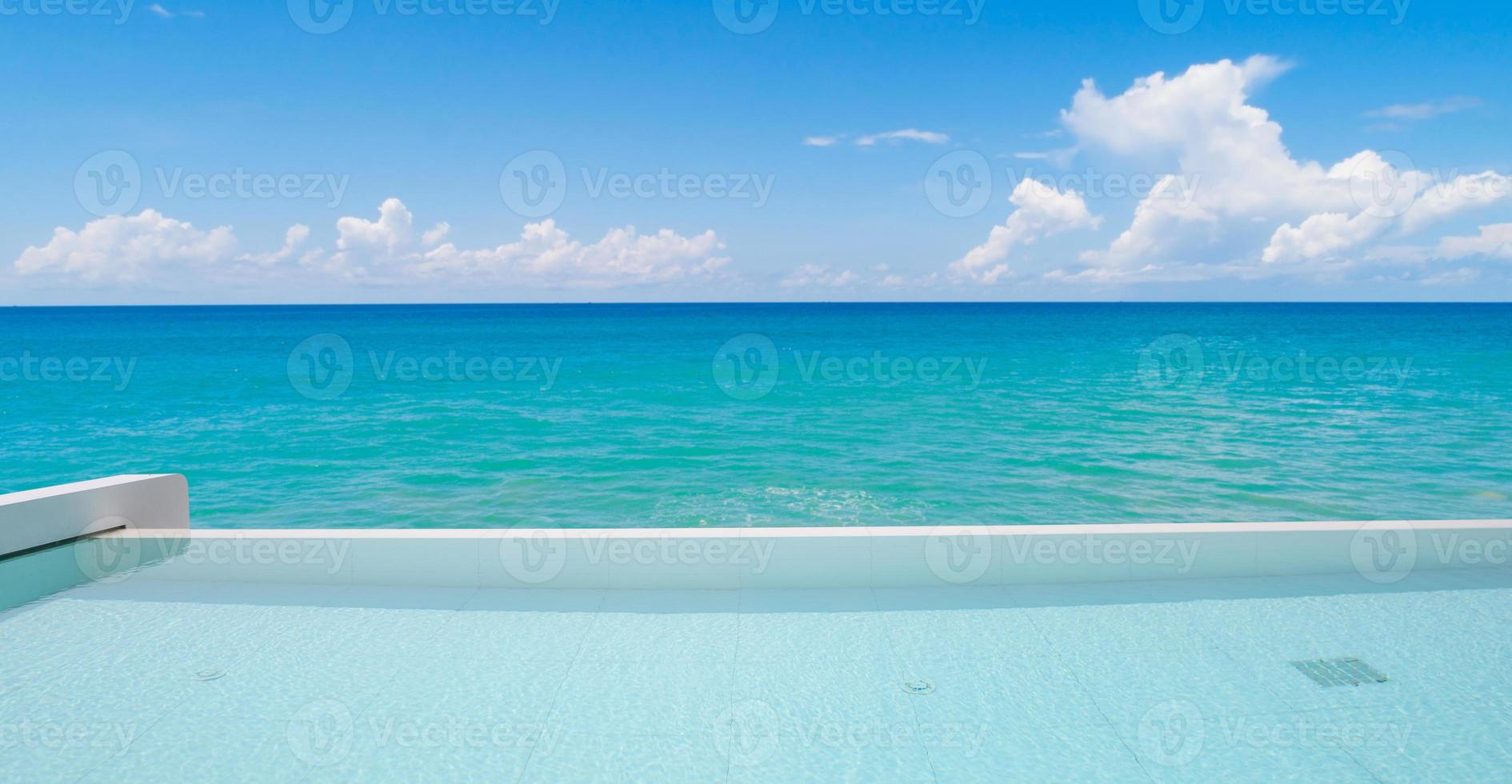 Swimming pool overlooking view tropical sea and clear blue sky background. Summer holiday and Travel background concept photo