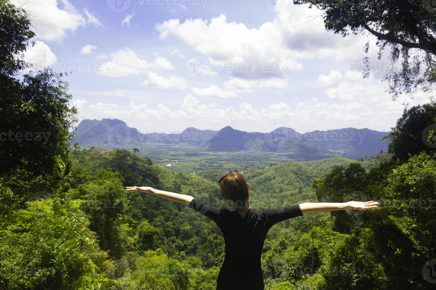 A women standing on cliff and see over view in nature.Tourist show  hands up and enjoying fresh air. A women enjoying free happiness in beautiful Thailand landscape. photo