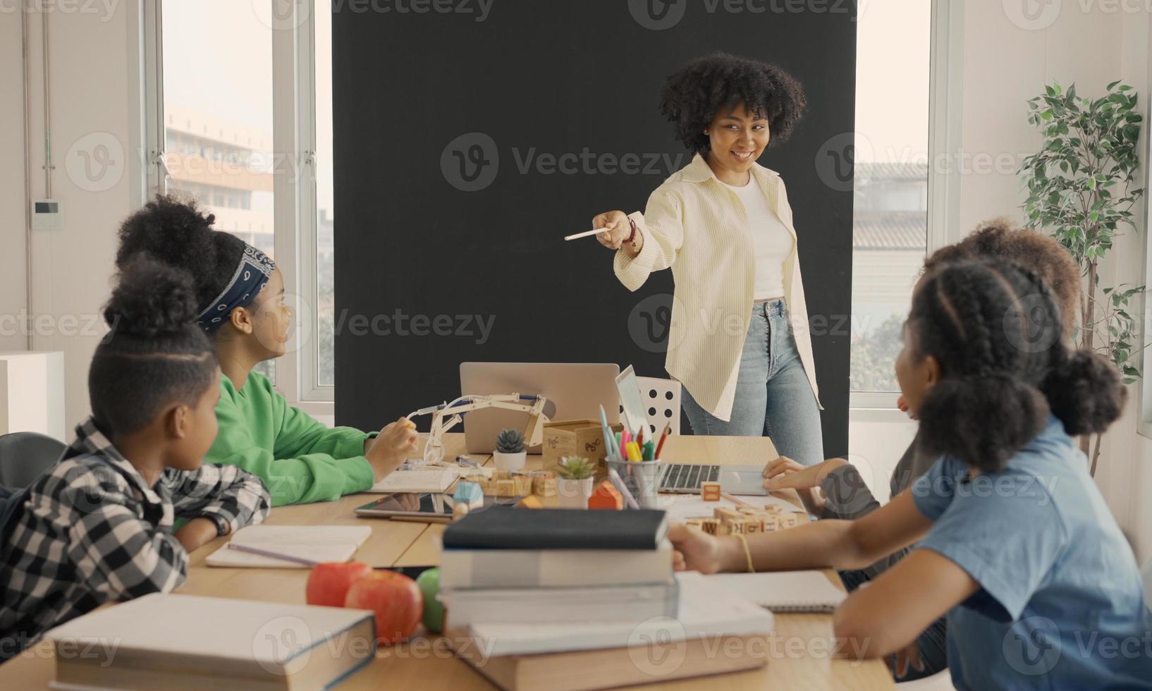 Classroom with diverse learners of happily African American students and teacher doing activities together. The teacher is teaching, guiding and talking to the children in diverse. photo