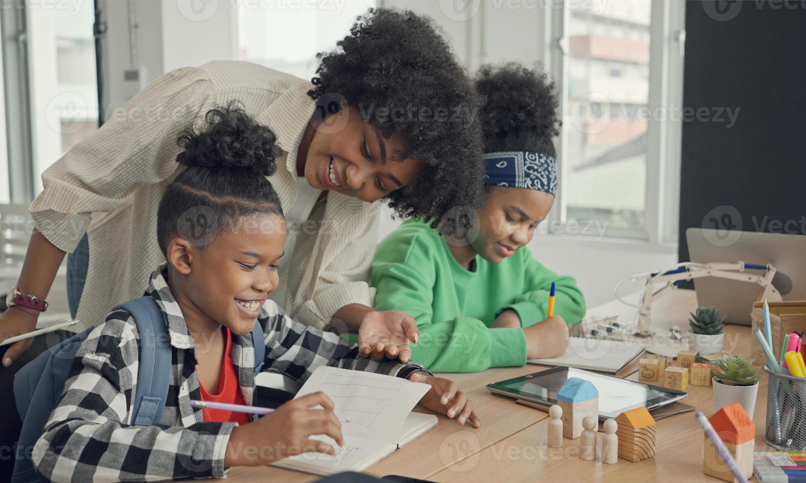 salón de clases con diversos estudiantes de estudiantes afroamericanos felices y maestros haciendo actividades juntos. el maestro está enseñando, guiando y hablando con los niños en diversos. foto