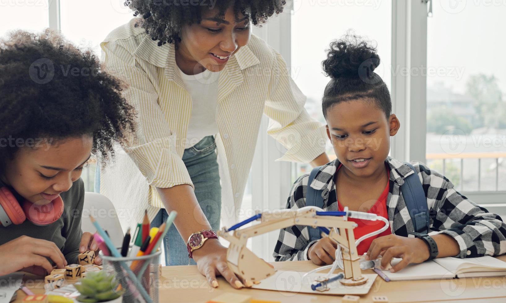 salón de clases con diversos estudiantes de estudiantes afroamericanos felices y maestros haciendo actividades juntos. el maestro está enseñando, guiando y hablando con los niños en diversos. foto