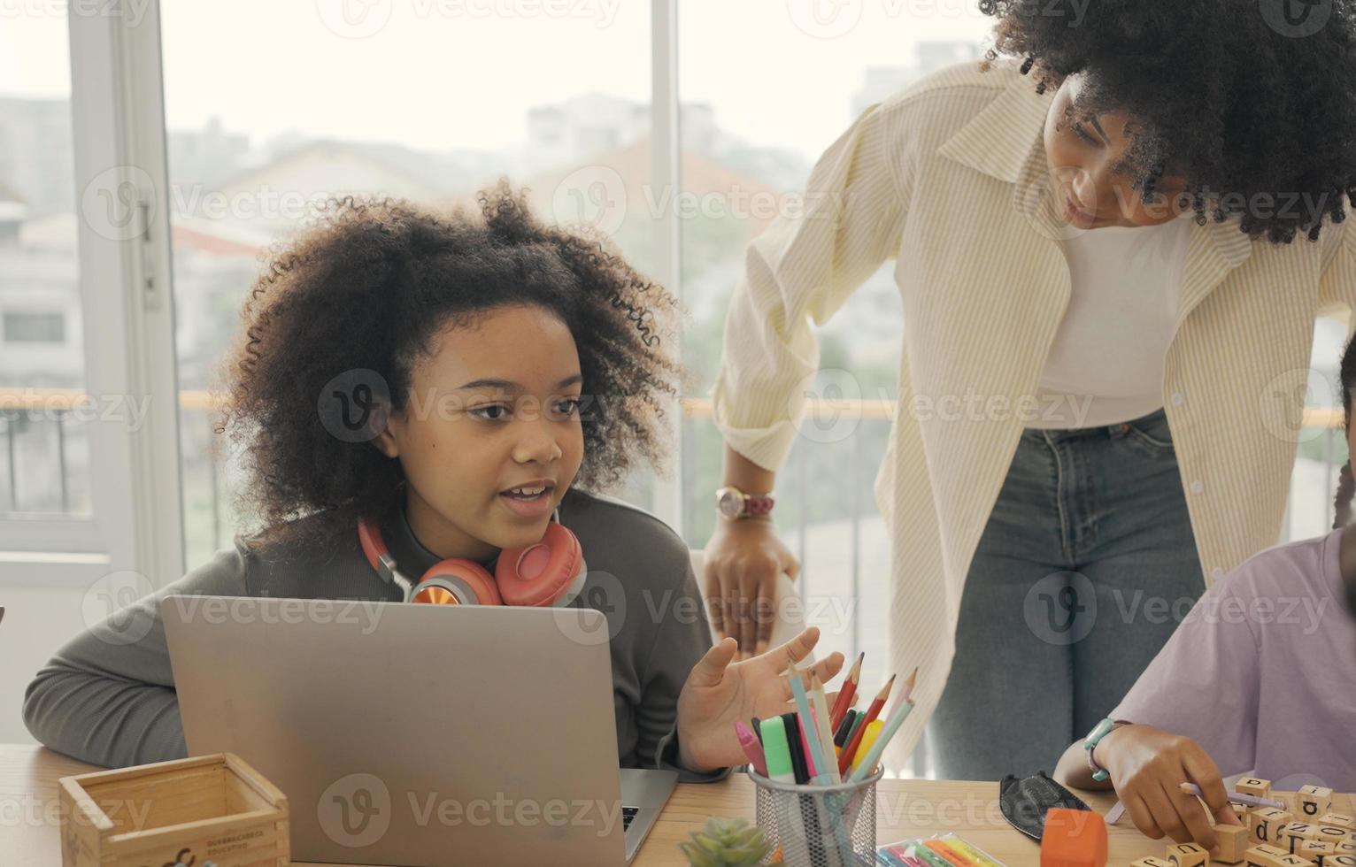 Classroom with diverse learners of happily African American students and teacher doing activities together. The teacher is teaching, guiding and talking to the children in diverse. photo