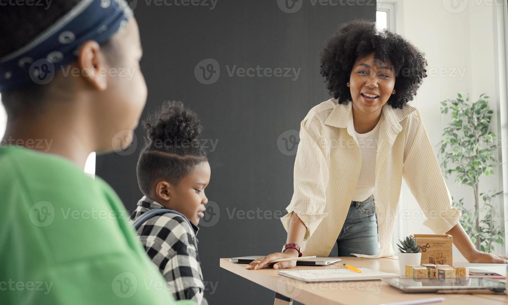 salón de clases con diversos estudiantes de estudiantes afroamericanos felices y maestros haciendo actividades juntos. el maestro está enseñando, guiando y hablando con los niños en diversos. foto