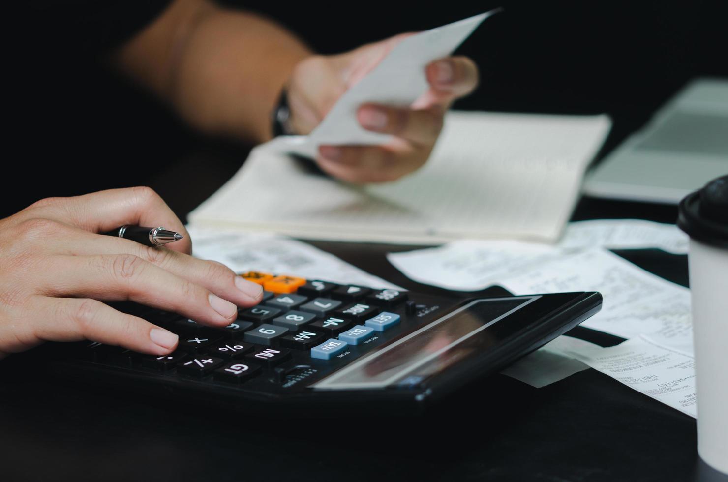 mano de hombre con gastos de pluma y calculadora o recibo de impuestos. concepto de finanzas empresariales. foto