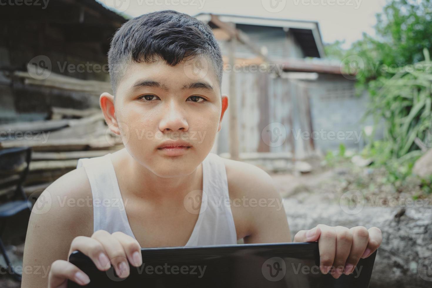 la cara de un estudiante rural pobre que estudia en línea con una computadora portátil hasta que sus ojos miran la cámara. distancia de educación en el hogar aprender en línea internet rural, falta de equipo educativo foto