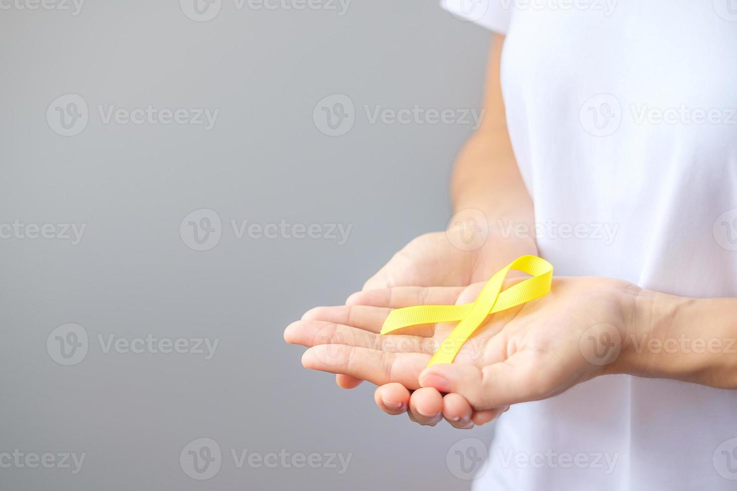 hand holding Yellow Ribbon for supporting people living and illness. September Suicide prevention day, Childhood, Sarcoma and bone cancer awareness month concept photo