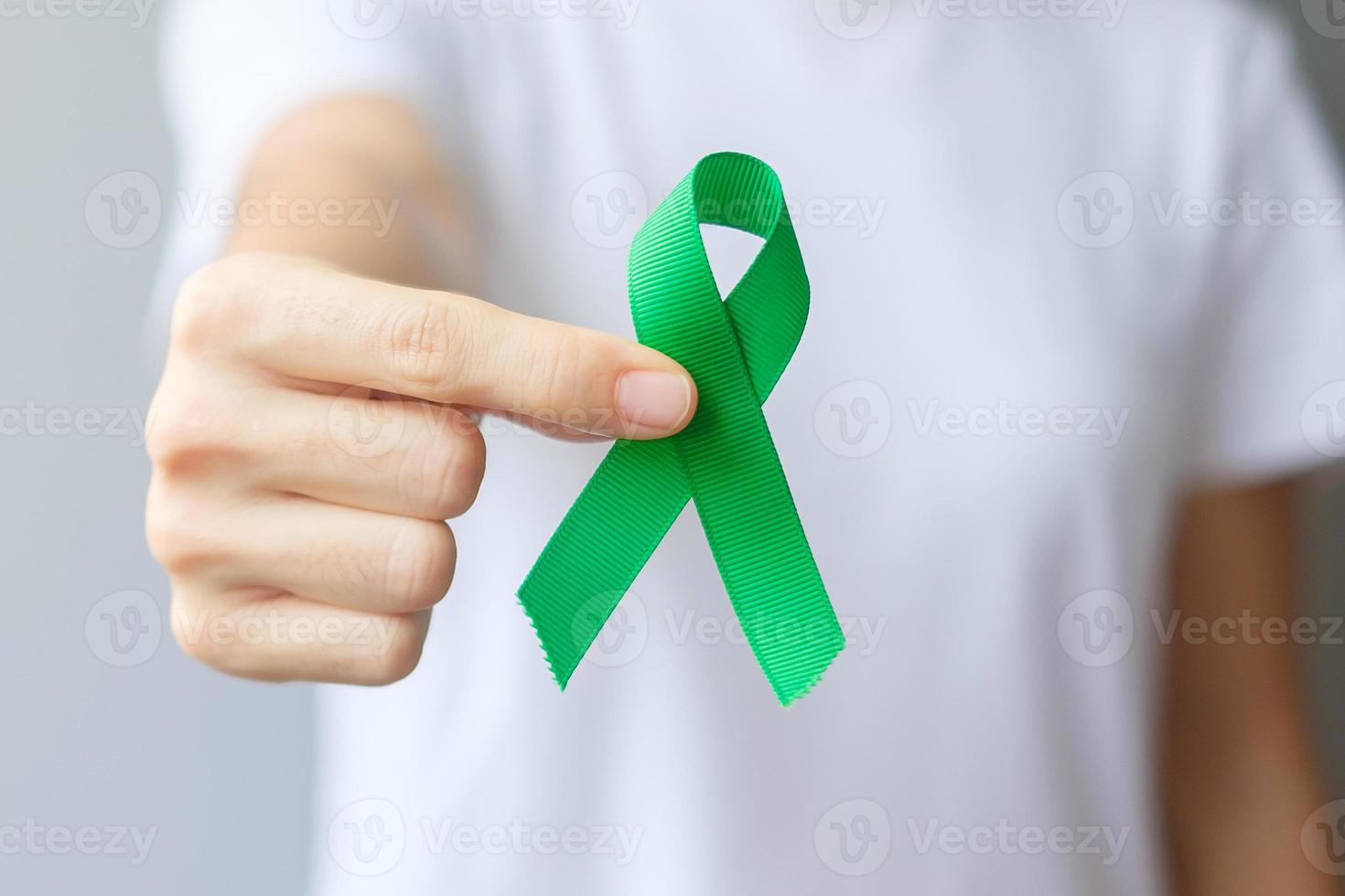 mano que sostiene la cinta verde para el hígado, las vesículas biliares, las vías biliares, el cuello uterino, el cáncer de riñón y el mes de concientización sobre el linfoma. concepto de salud y día mundial del cáncer foto