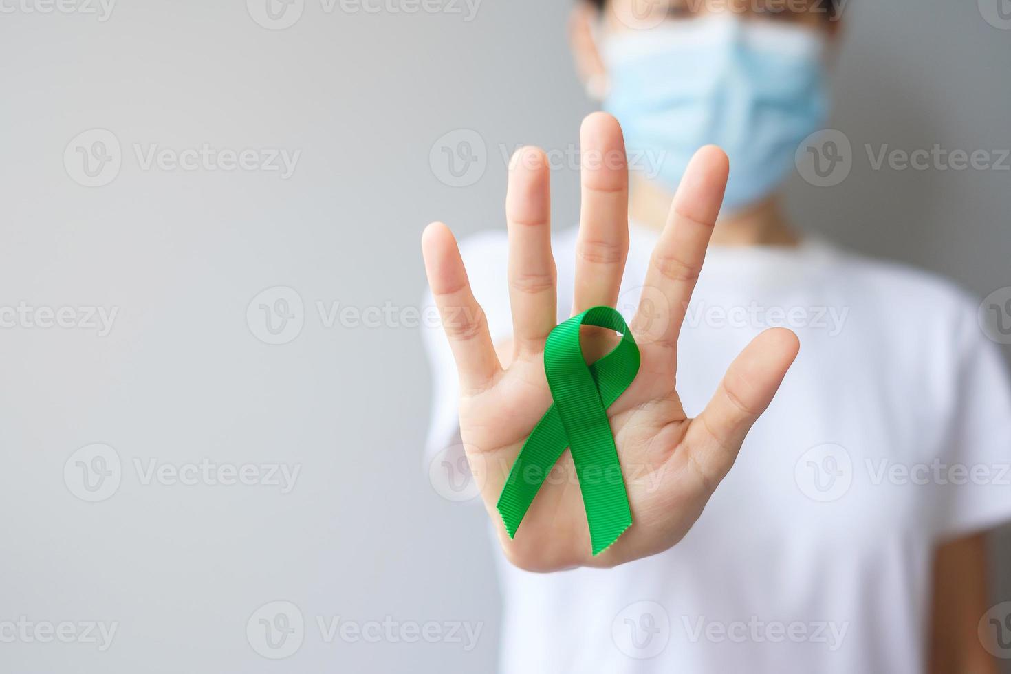 mano que sostiene la cinta verde para el hígado, las vesículas biliares, las vías biliares, el cuello uterino, el cáncer de riñón y el mes de concientización sobre el linfoma. concepto de salud y día mundial del cáncer foto