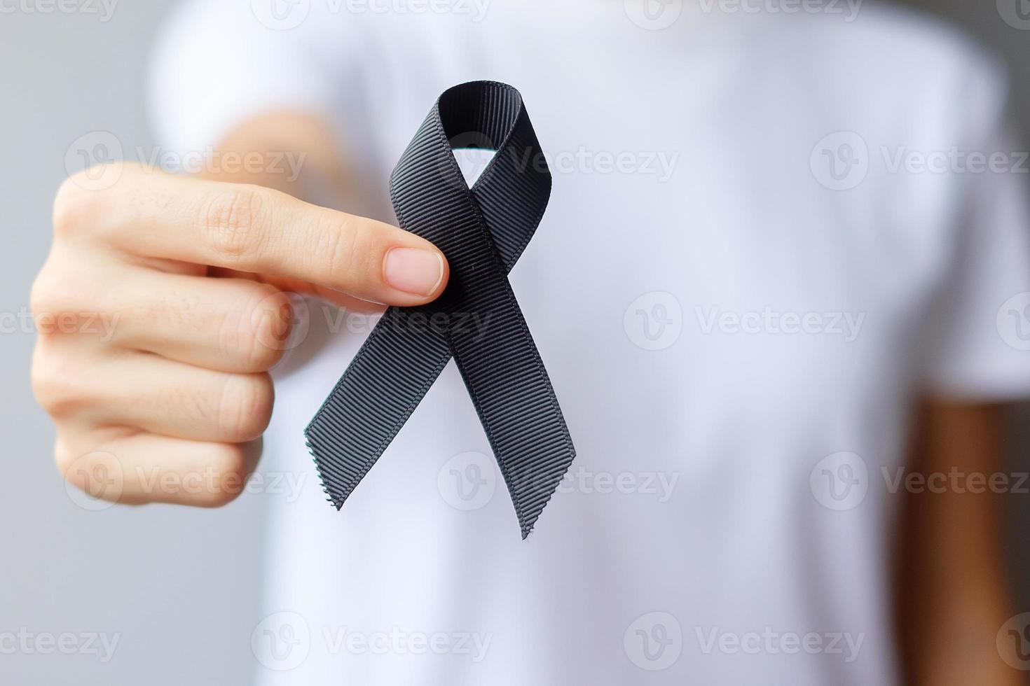 Woman holding black Ribbon for Melanoma and skin cancer, Vaccine injury awareness month, grief and rest in peace. Healthcare and Racist concept photo