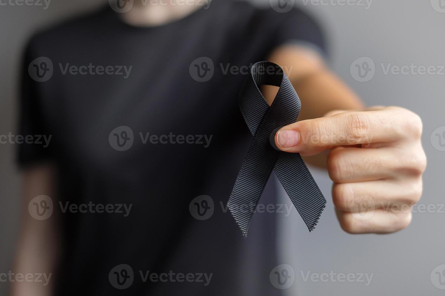 mujer con cinta negra para melanoma y cáncer de piel, mes de concientización sobre lesiones por vacunas, dolor y descanso en paz. salud y concepto racista foto