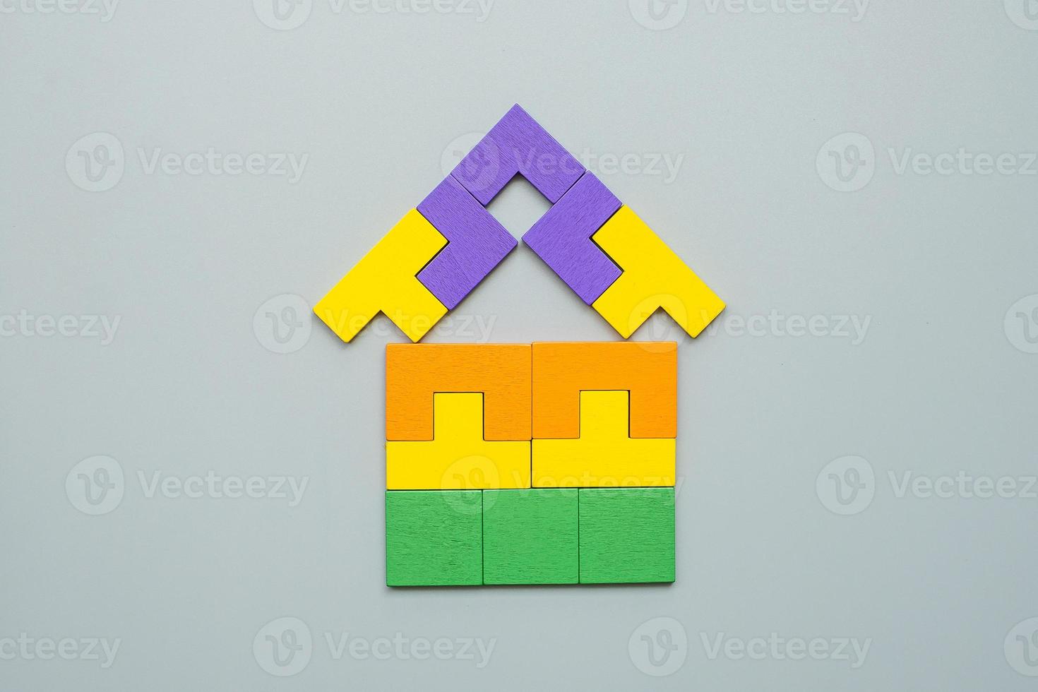 Home shape block with colorful wood puzzle pieces on gray background. logical thinking, business logic, solutions, rational, house, real estate and strategy concepts photo