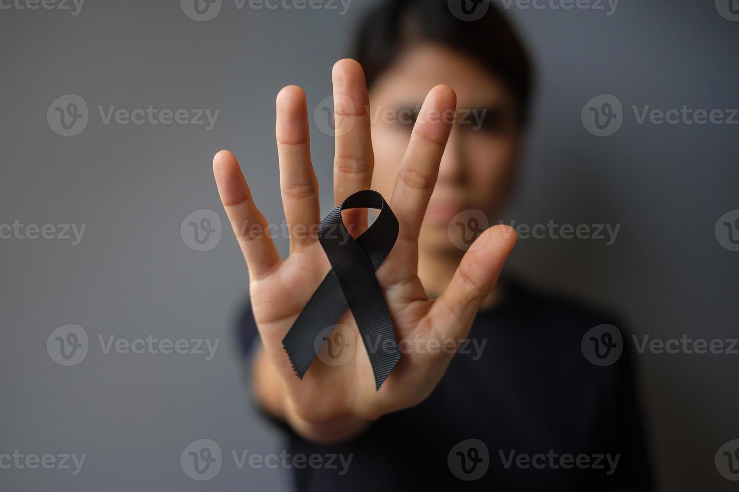 mujer con cinta negra para melanoma y cáncer de piel, mes de concientización sobre lesiones por vacunas, dolor y descanso en paz. salud y concepto racista foto