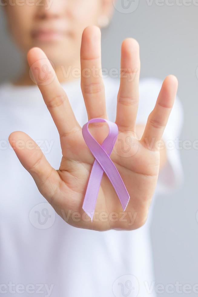 World cancer day. Woman hand holding Lavender purple ribbon for supporting people living and illness. Healthcare and medical concept photo