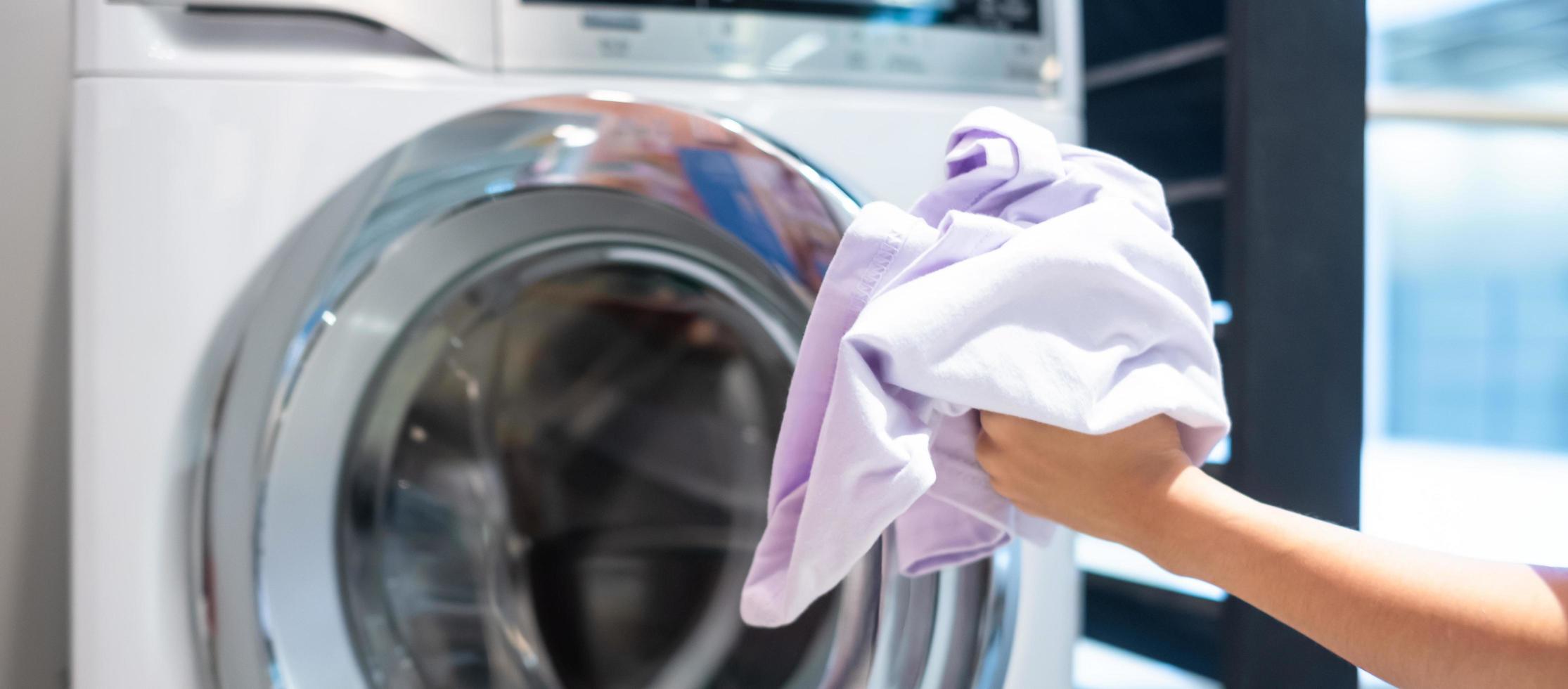 Housewife Woman hand holding clothes inside Washing Machine in laundry room photo