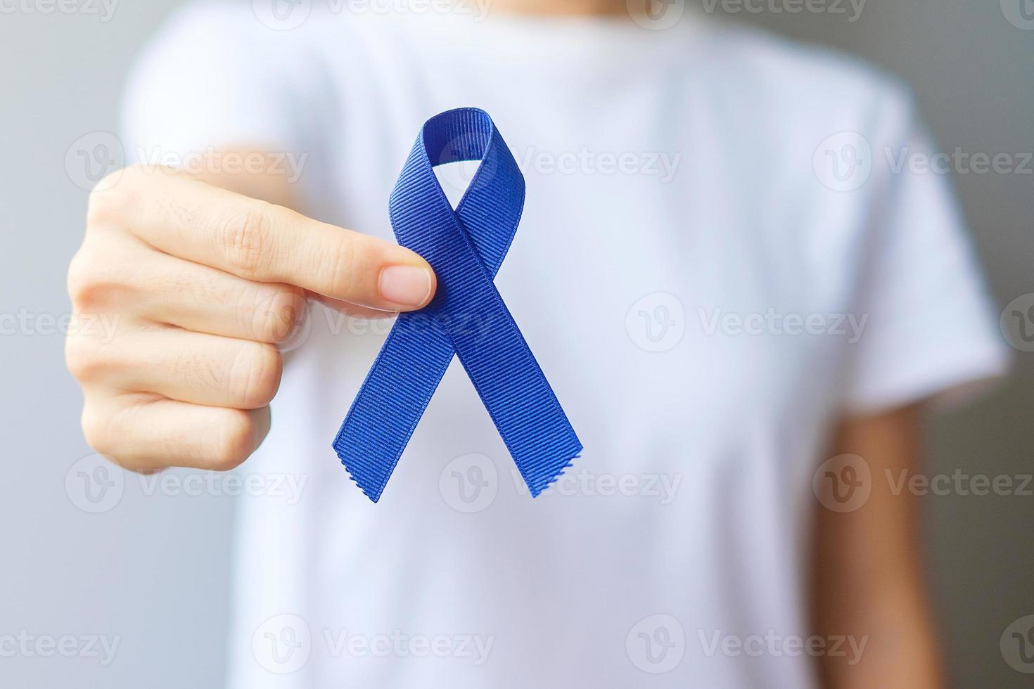 marzo mes de concientización sobre el cáncer colorrectal, mujer sosteniendo una cinta azul oscuro para apoyar a las personas que viven y están enfermas. concepto de salud, esperanza y día mundial contra el cáncer foto