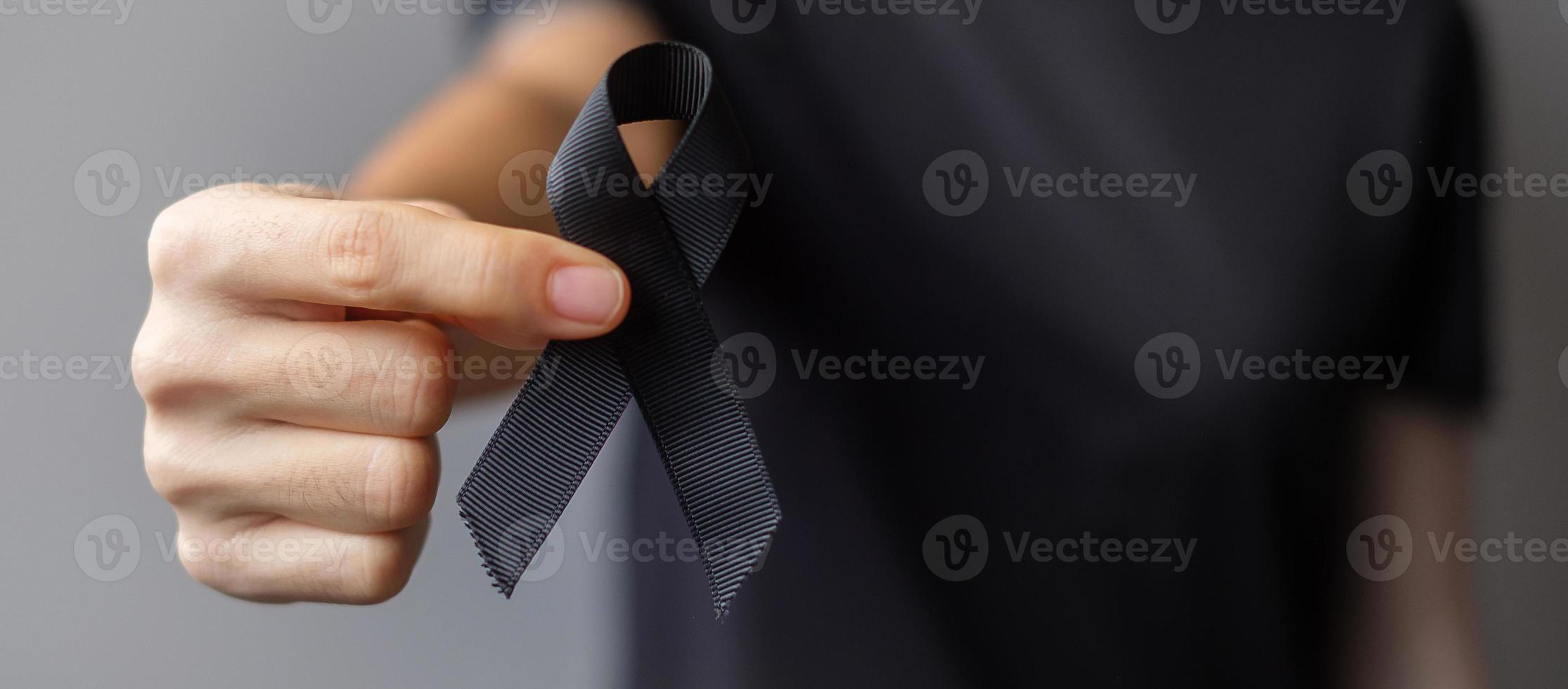 Woman holding black Ribbon for Melanoma and skin cancer, Vaccine injury awareness month, grief and rest in peace. Healthcare and Racist concept photo