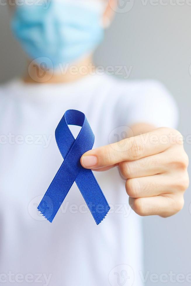 marzo mes de concientización sobre el cáncer colorrectal, mujer sosteniendo una cinta azul oscuro para apoyar a las personas que viven y están enfermas. concepto de salud, esperanza y día mundial contra el cáncer foto