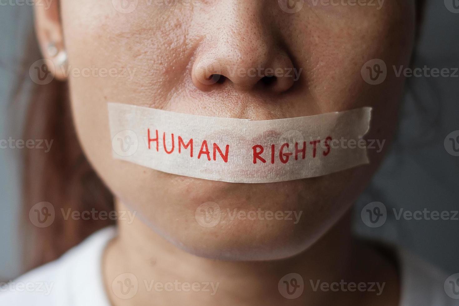 woman with mouth sealed in adhesive tape with Human rights message. Free of speech, freedom of press, Protest dictatorship, democracy, liberty, equality and fraternity concepts photo