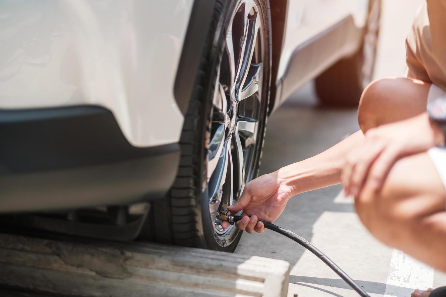 man driver hand inflating tires of vehicle, removing tire valve nitrogen cap for checking air pressure and filling air on car wheel at gas station. self service, maintenance and safety photo