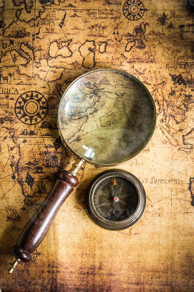 Old vintage retro compass and magnifying glass on ancient map.The map used for background is in Public domain. photo