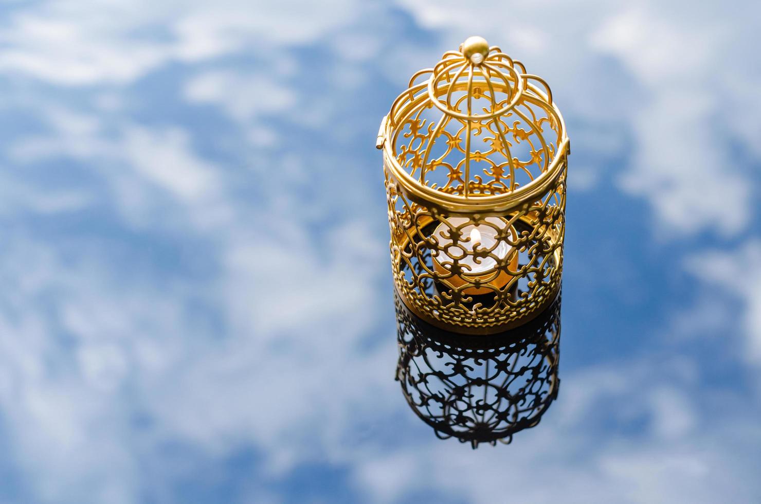 Selective focus of golden lantern with reflection blurred background of cloud and sky for Islamic new year concept. photo