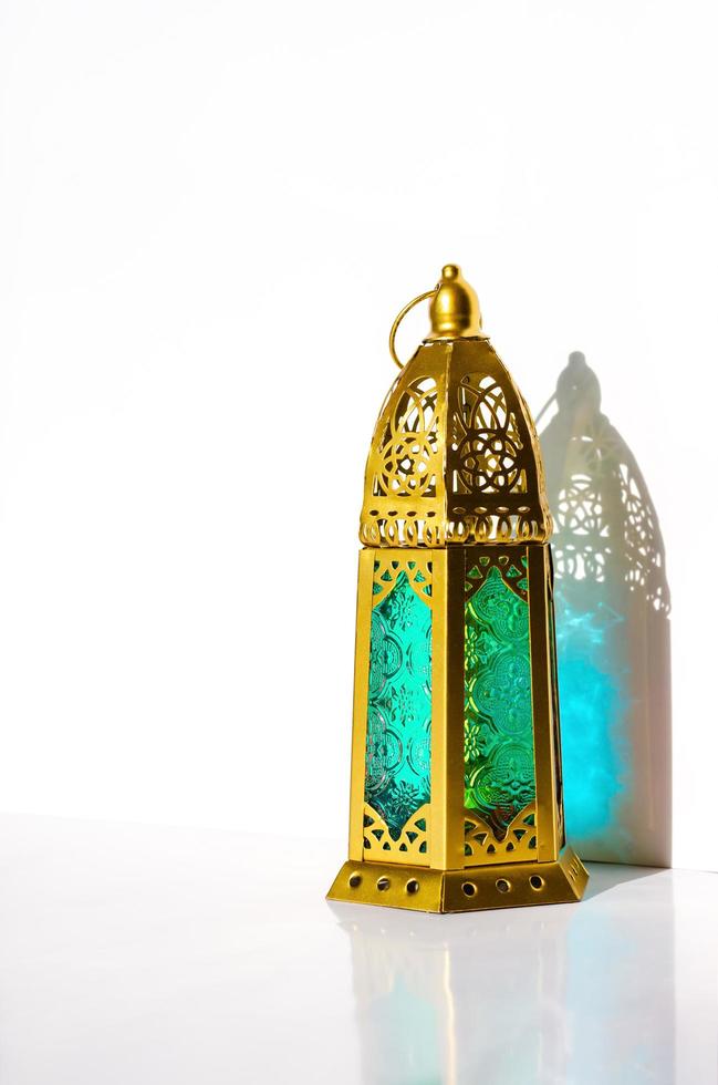 Golden lantern with shadow from sun light on white background. photo