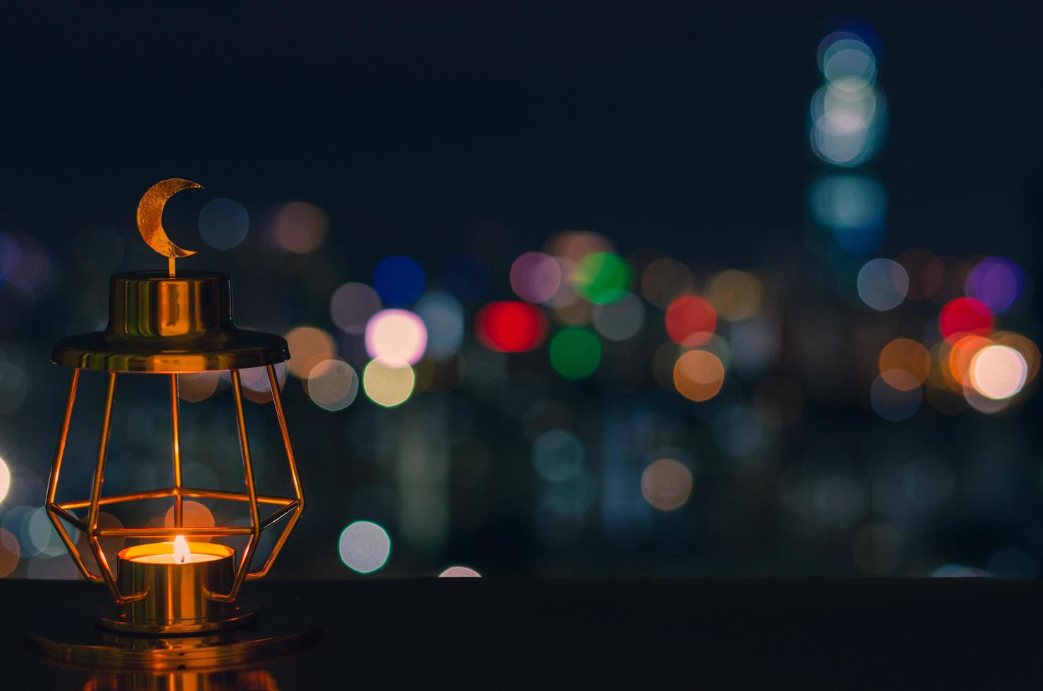 linterna dorada moderna que tiene el símbolo de la luna en la parte superior con coloridas luces de bokeh de la ciudad en el fondo oscuro foto