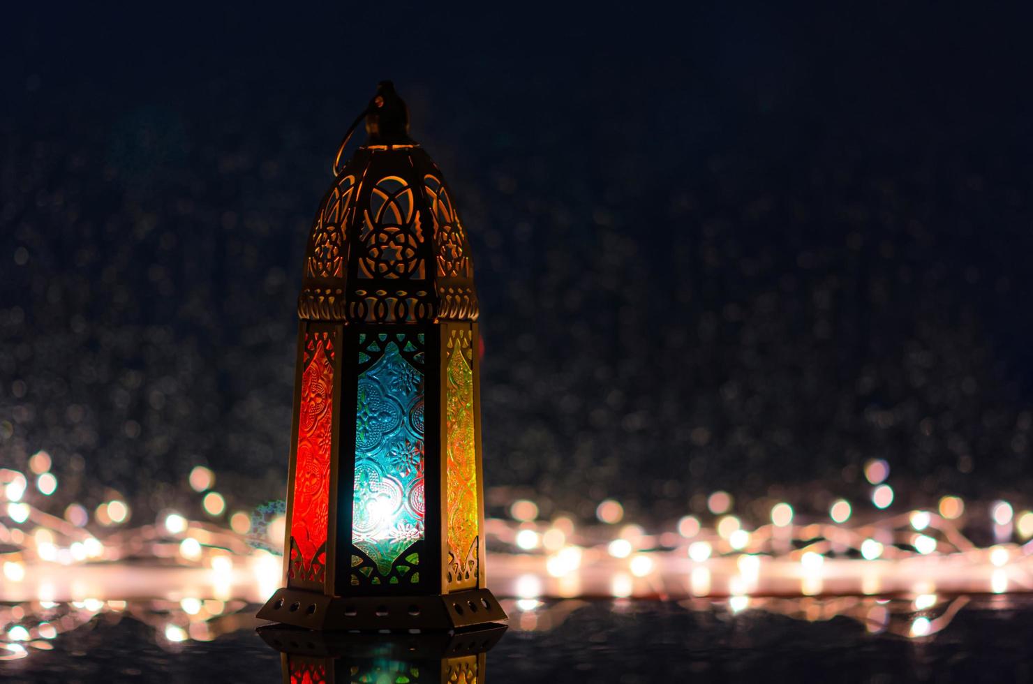 Selective focus on blue mirror of lantern with lights decorating for Islamic new year put at window with rain drop at background. photo