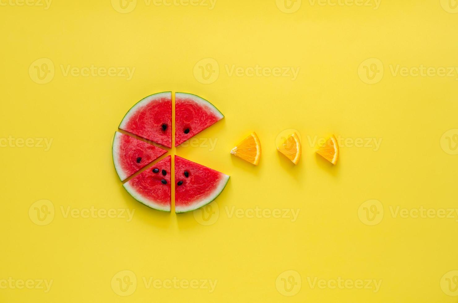 Watermelon eating small slice of orange on yellow background. photo