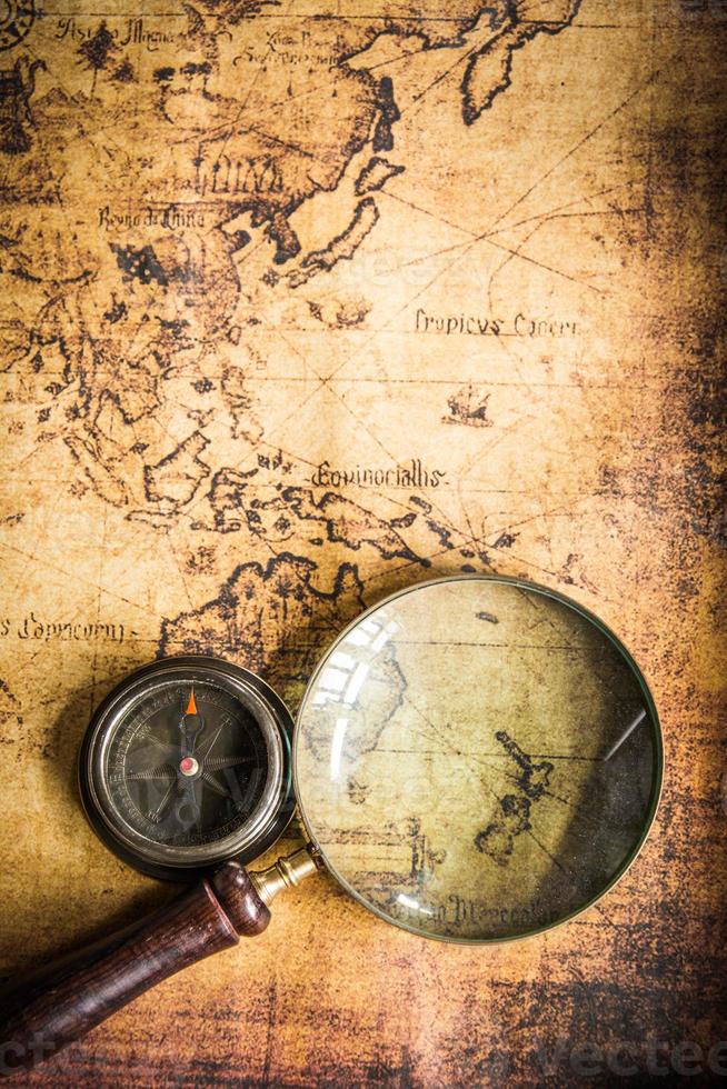 Old vintage retro compass and magnifying glass on ancient map.The map used for background is in Public domain. photo