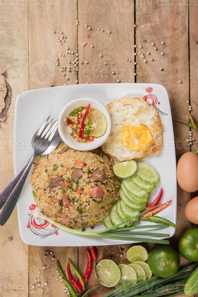 fried rice with vegetables, meat and fried eggs served on a plate with chopsticks photo