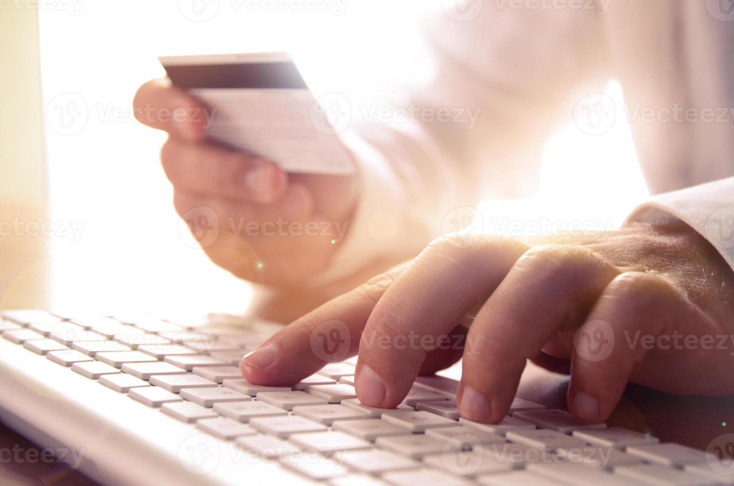 primer plano de las manos del hombre sosteniendo la tarjeta de crédito y usando el teclado de la computadora. concepto de comercio electrónico, compras en línea, banca electrónica, seguridad en Internet. foto