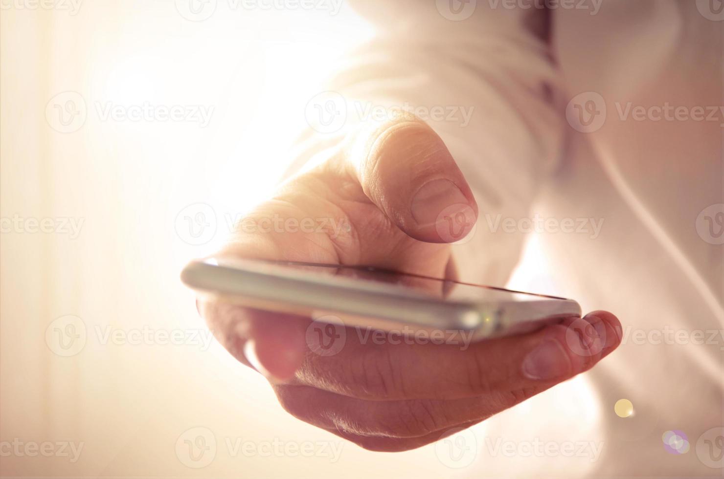 Mans hand holding and using a smartphone. photo