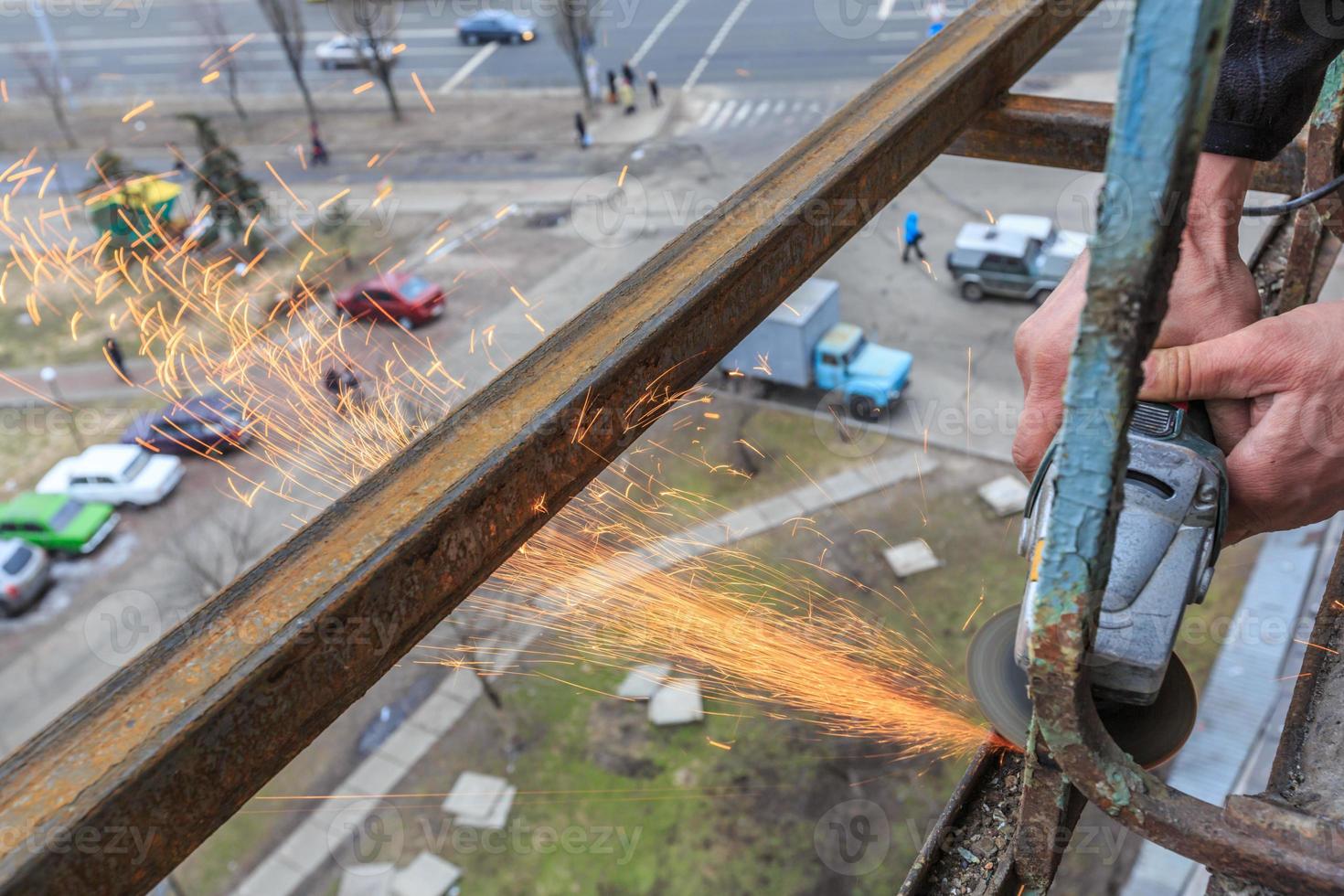 un trabajador corta metal con un molinillo. foto