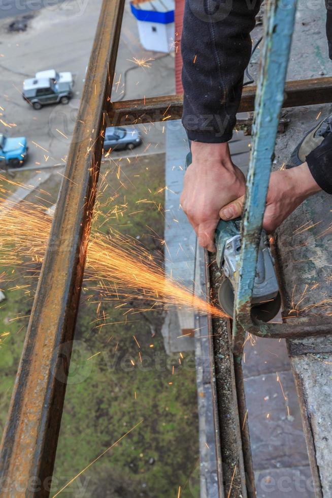 A worker cuts metal with a grinder. photo