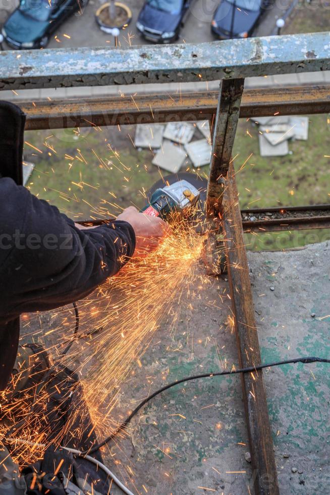 un trabajador corta metal con un molinillo. foto