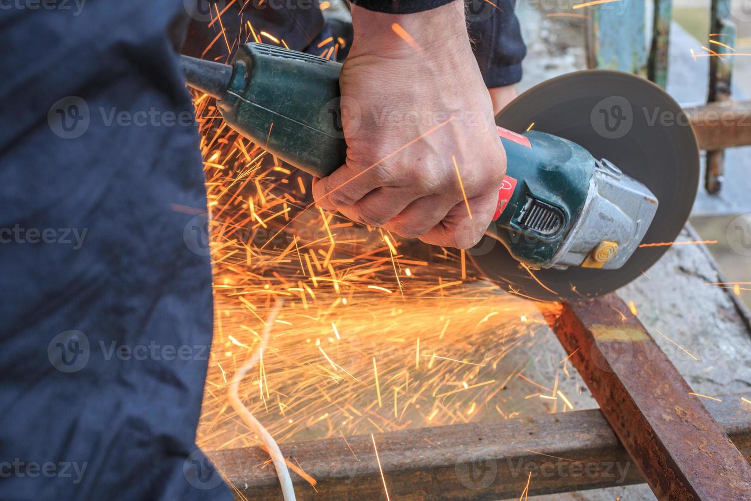 A worker cuts metal with a grinder. photo