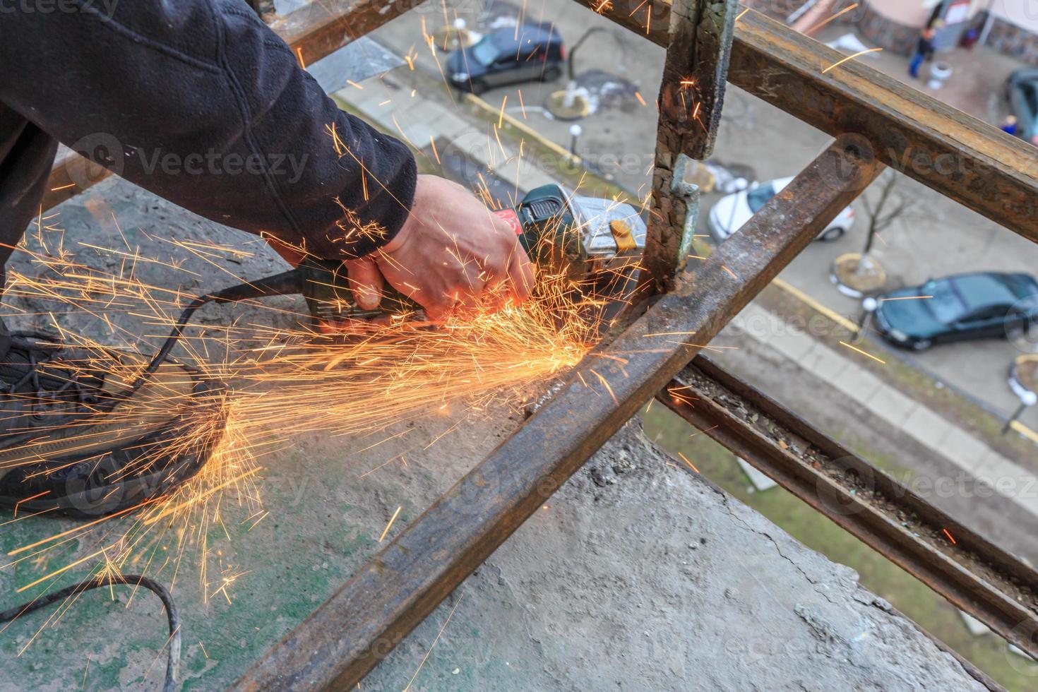 un trabajador corta metal con un molinillo. foto