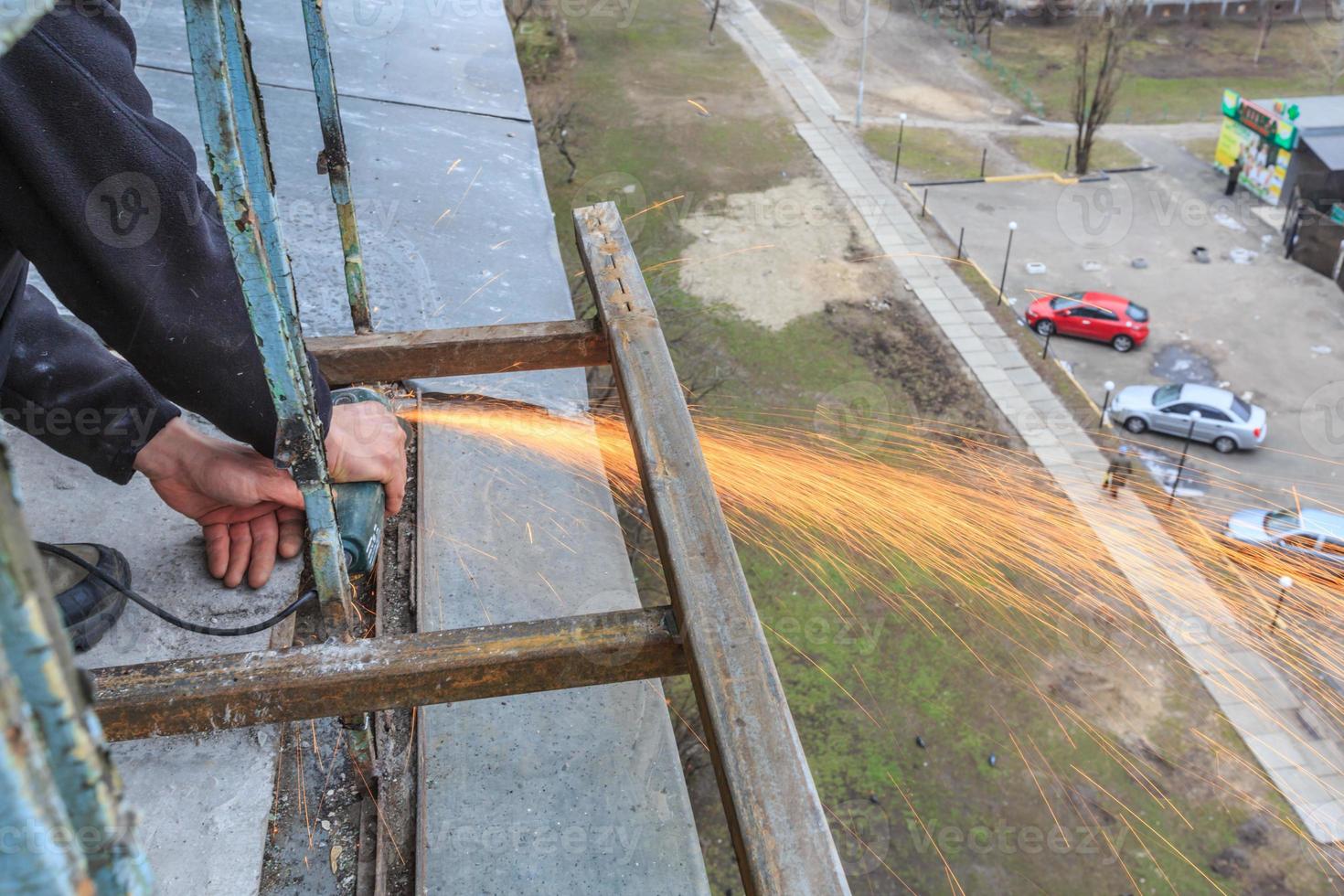 un trabajador corta metal con un molinillo. foto