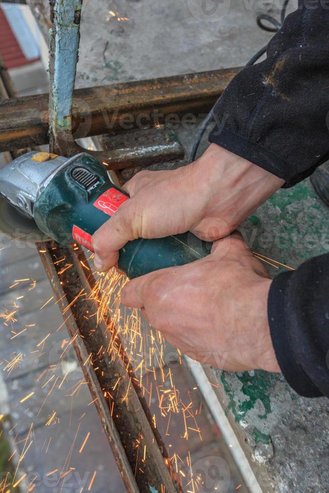 un trabajador corta metal con un molinillo. foto