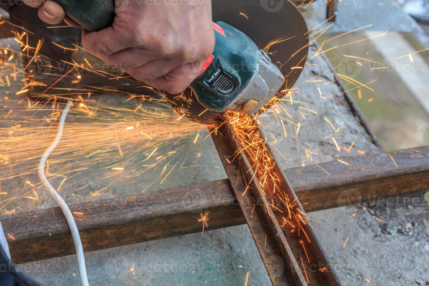 un trabajador corta metal con un molinillo. foto