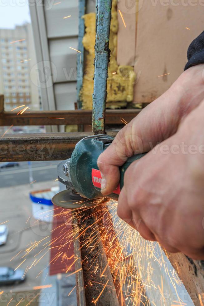 un trabajador corta metal con un molinillo. foto