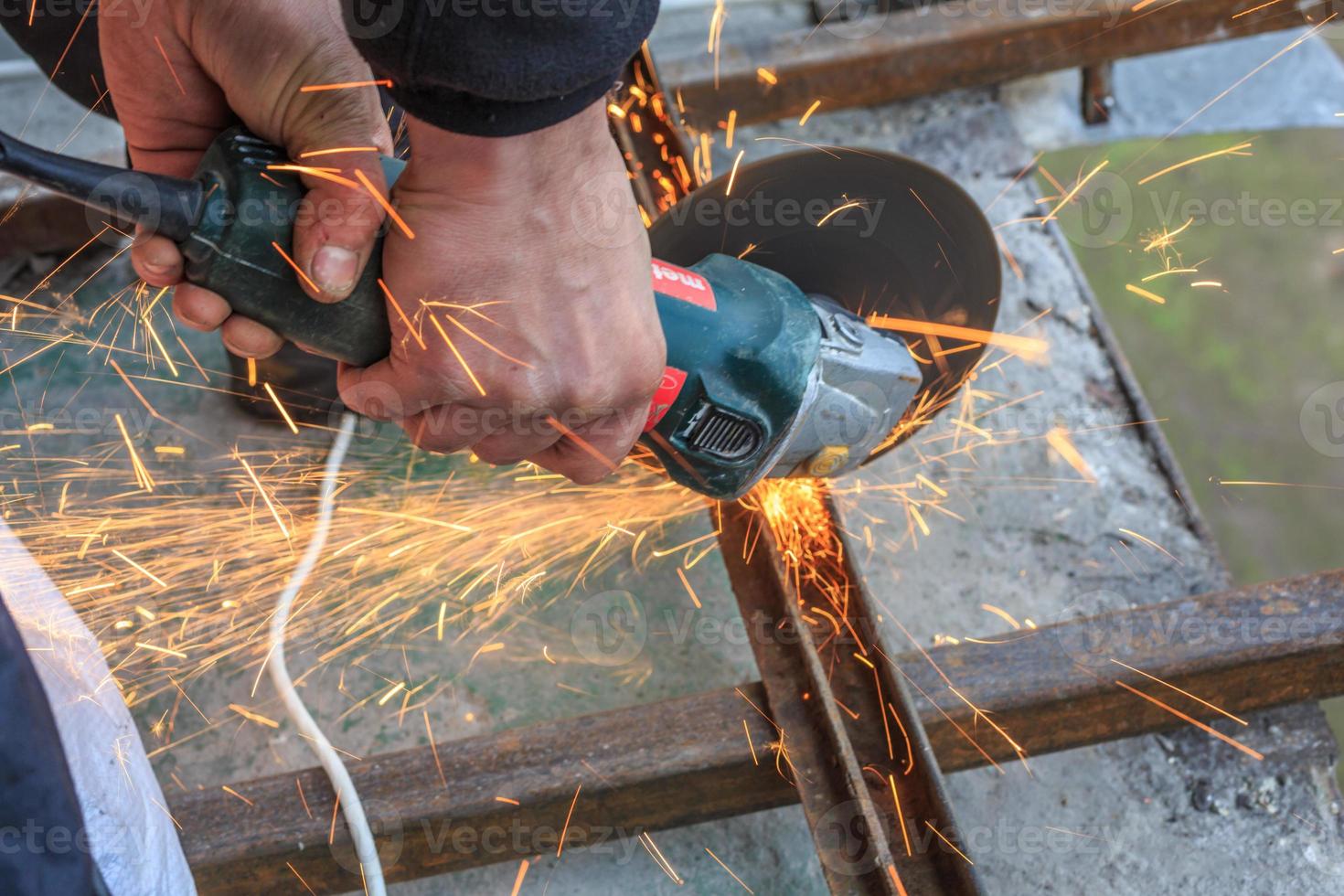 A worker cuts metal with a grinder. photo