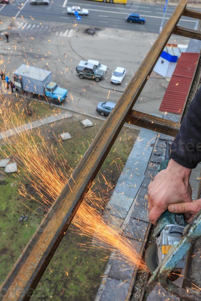 A worker cuts metal with a grinder. photo