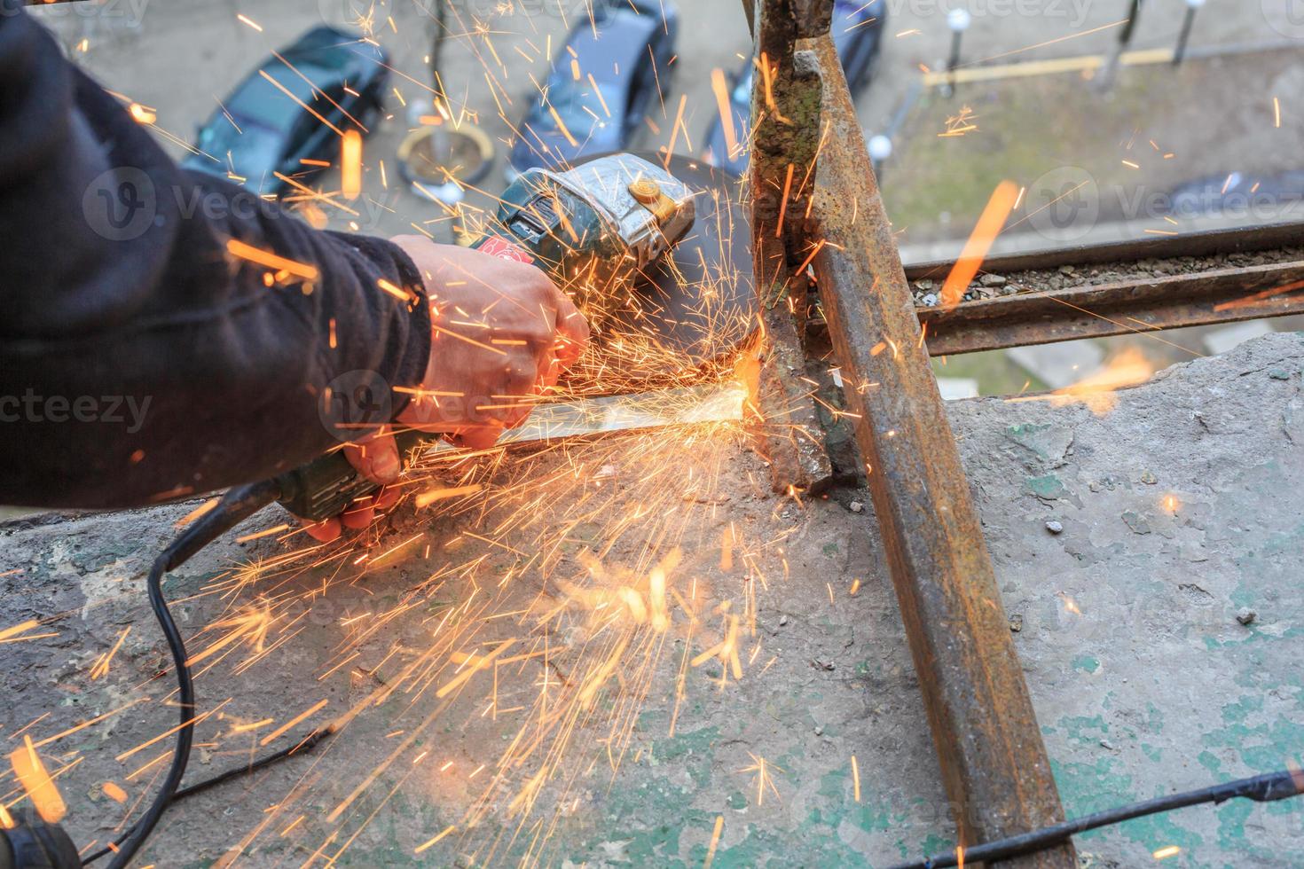 un trabajador corta metal con un molinillo. foto