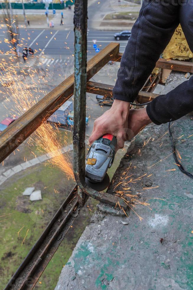 A worker cuts metal with a grinder. photo